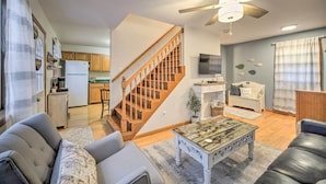 A spacious living room with a wooden staircase, a dining area, and a kitchen with wooden cabinets. - Lake Luzerne Home w/ Fire Pit on Hudson River (Lake Luzerne)