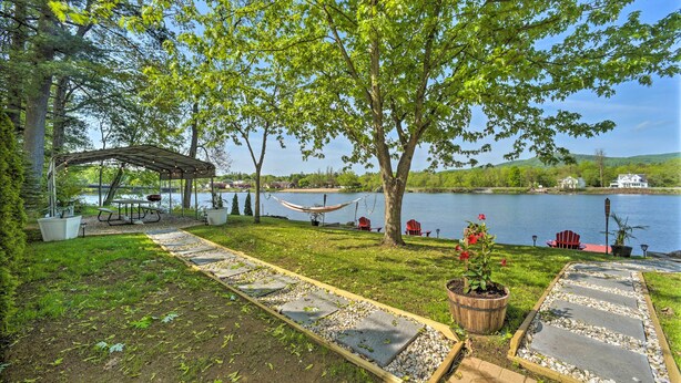 A serene lakeside patio with a hammock, picnic table, and potted plants. - Lake Luzerne Home w/ Fire Pit on Hudson River (Lake Luzerne)