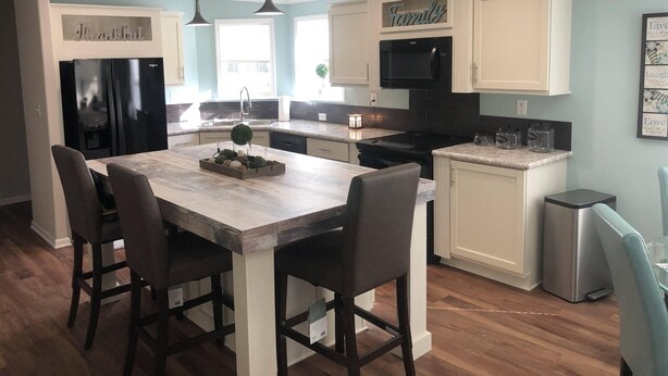Una cocina moderna con una isla central, sillas de madera oscura y un refrigerador de acero inoxidable.