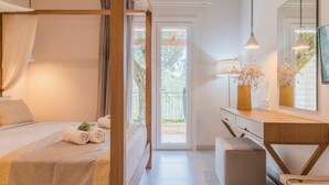 Een slaapkamer met een hemelbed, een nachtkastje met een bloemenvaas en een uitzicht op de omgeving door een glazen deur.