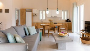 Een moderne woonkamer met een bank, salontafel en een eetgedeelte met houten meubels.