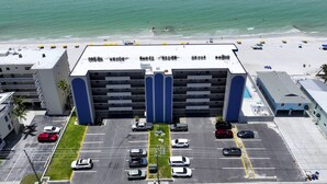 Un hotel de varios pisos con estacionamiento, vista al mar y zona de piscina.