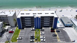 Un hotel de varios pisos con estacionamiento, vista al mar y zona de piscina.