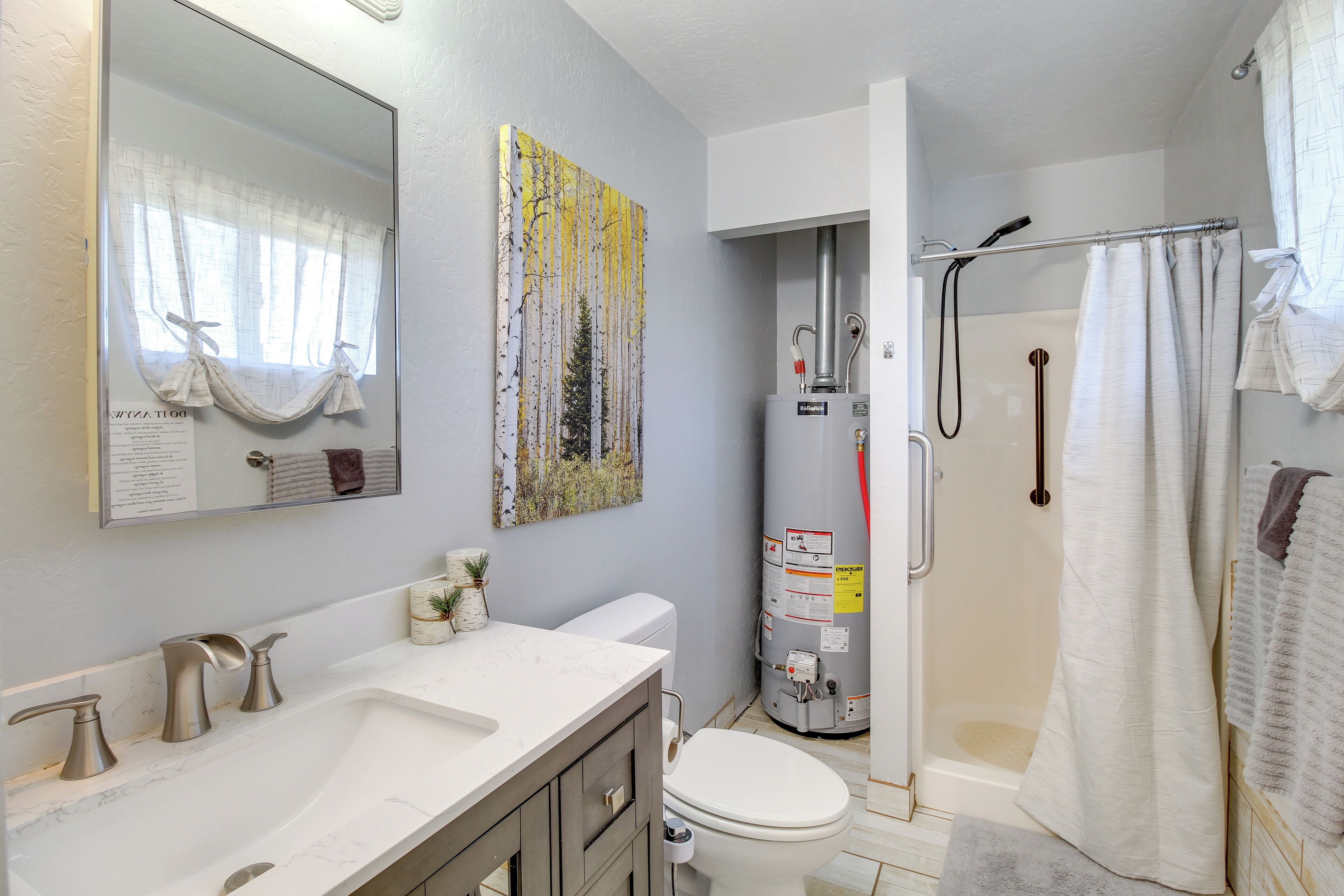 Une salle de bain avec un lavabo blanc, des toilettes, une douche et un grand miroir.