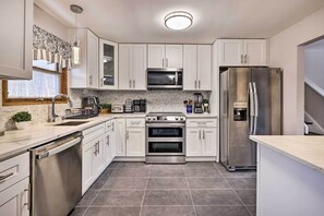A modern kitchen with white cabinets, stainless steel appliances, and a tiled backsplash. - Modern East Stroudsburg Home w/ Pool + Fire Pit (East Stroudsburg)