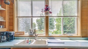 Una cocina con ventana, cafetera, lavamanos y un cartel que dice "COFFEE".