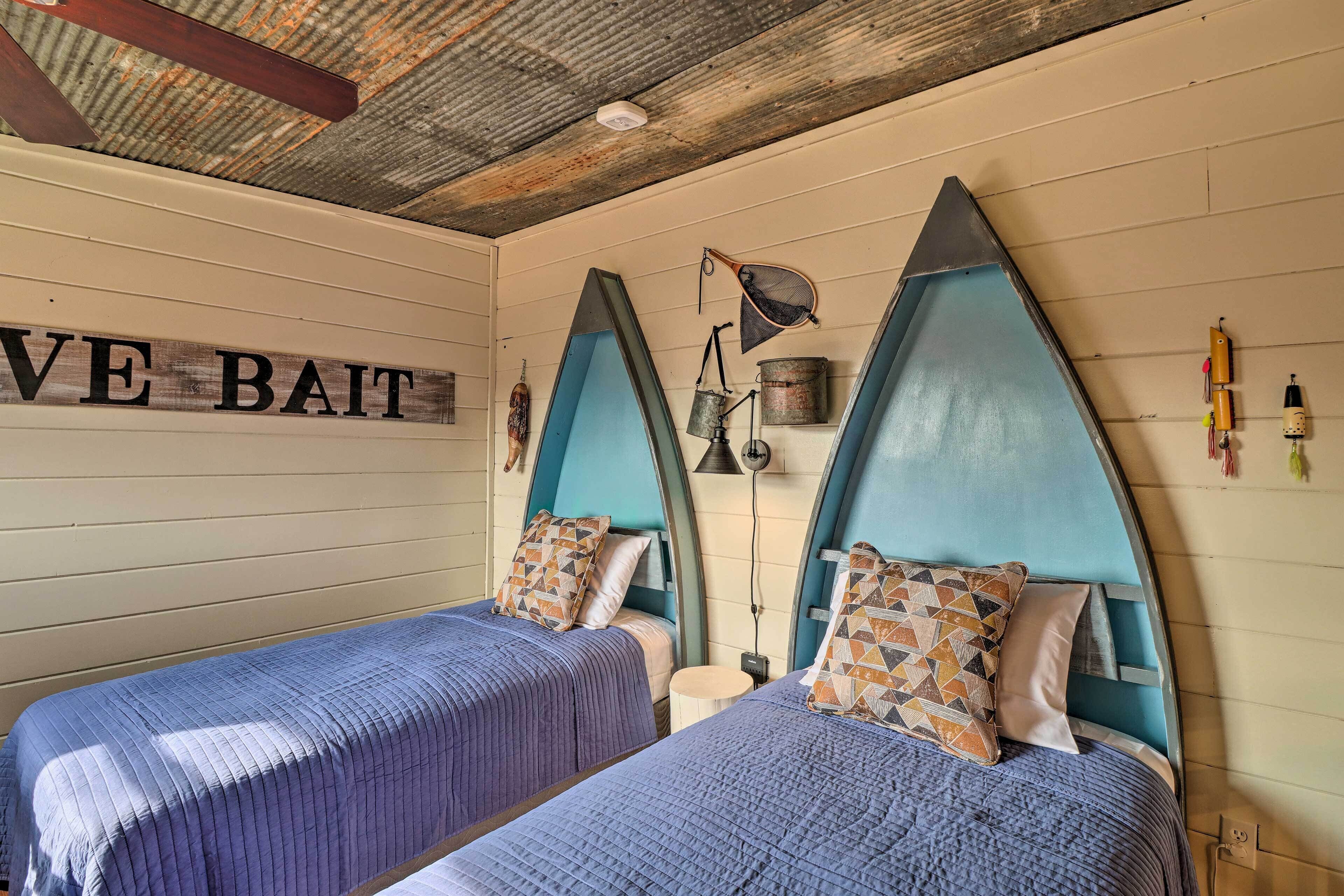 Une chambre avec deux lits, chacun doté d’une tête de lit bleue et d’oreillers à motifs. Une pancarte sur le mur indique : « E Bait ».