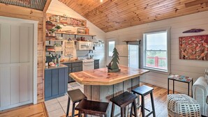 A kitchen with a wooden ceiling, a central island with stools, and a window with blinds. - Cheery Pet-Friendly Studio w/ Shared Fire Pit (Mountain View)