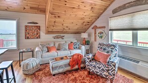 A cozy living room with a wooden ceiling, a grey sofa, a patterned armchair, and a red rug. - Cheery Pet-Friendly Studio w/ Shared Fire Pit (Mountain View)