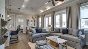 A spacious living room with a sectional sofa, a coffee table, and a dining area with a chandelier.