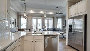A modern kitchen with a central island, stainless steel appliances, and a dining area with a sofa.
