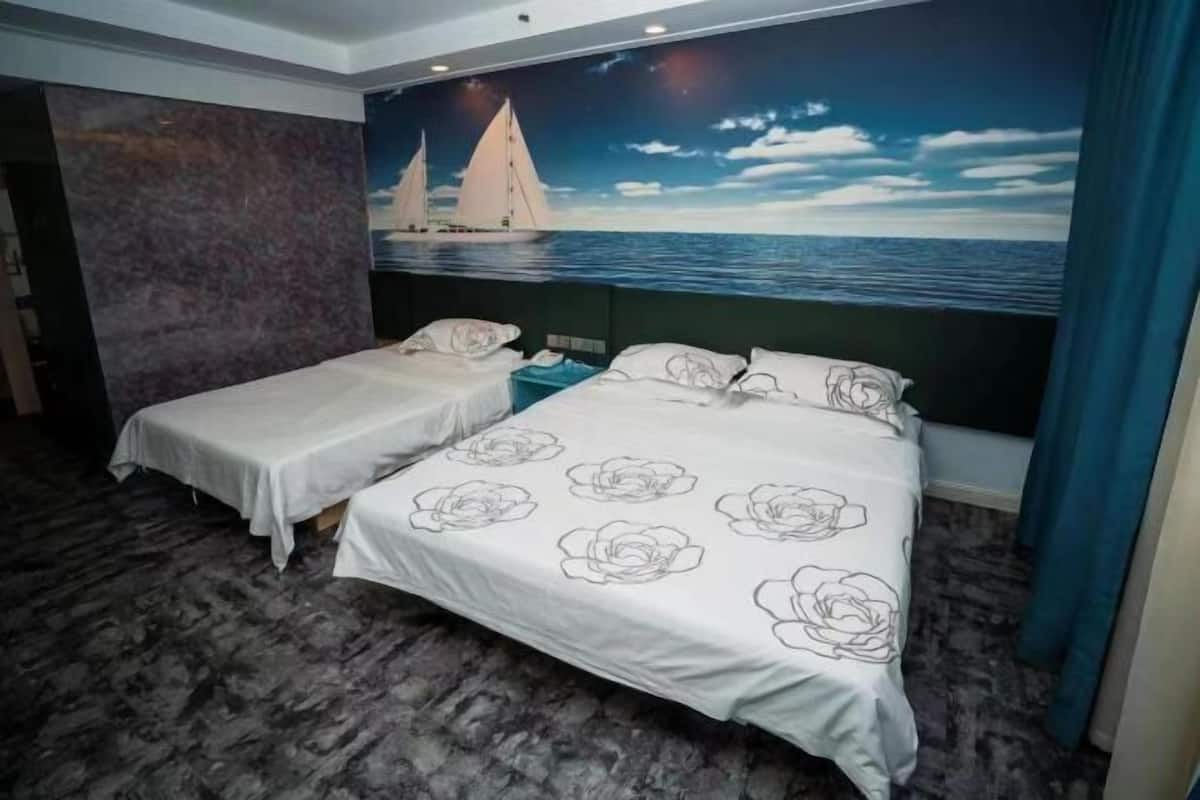 Een hotelkamer met twee enkele bedden, een muurschildering van zeilboten en een marmeren vloer.