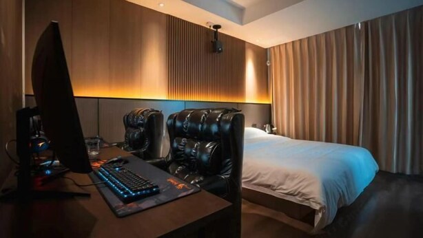 Ein Hotelzimmer mit Bett, Schreibtisch mit Computer, Stuhl und Kopfstütze.