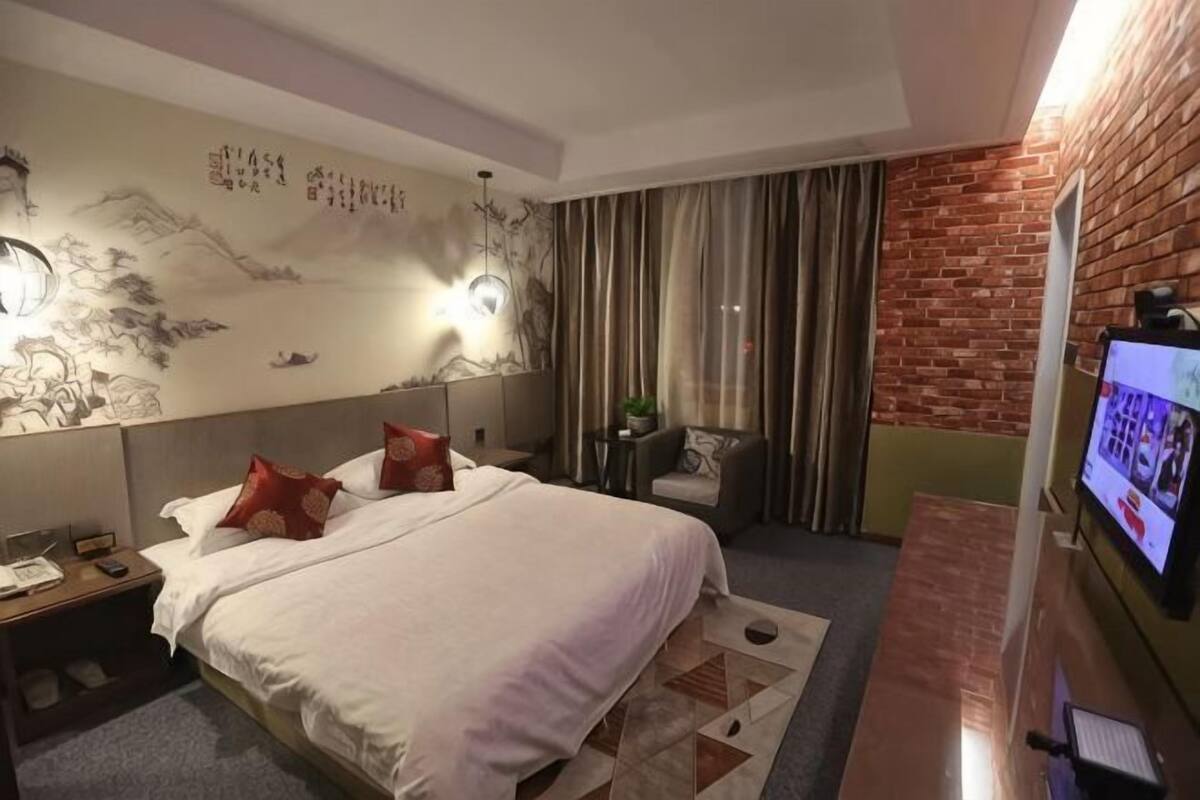 Een hotelkamer met een groot bed, een televisie, een bureau en een bakstenen muur.
