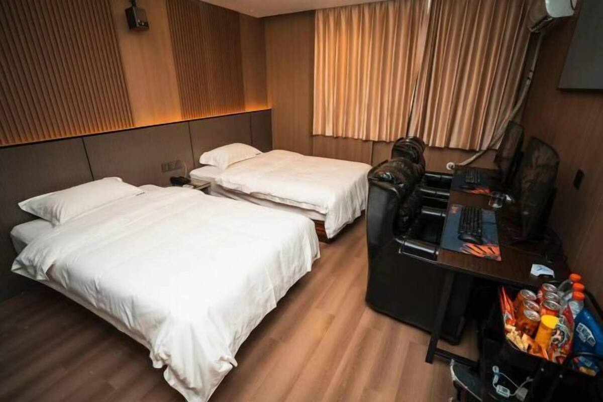 Een hotelkamer met twee bedden, een bureau met stoel en een minibar.