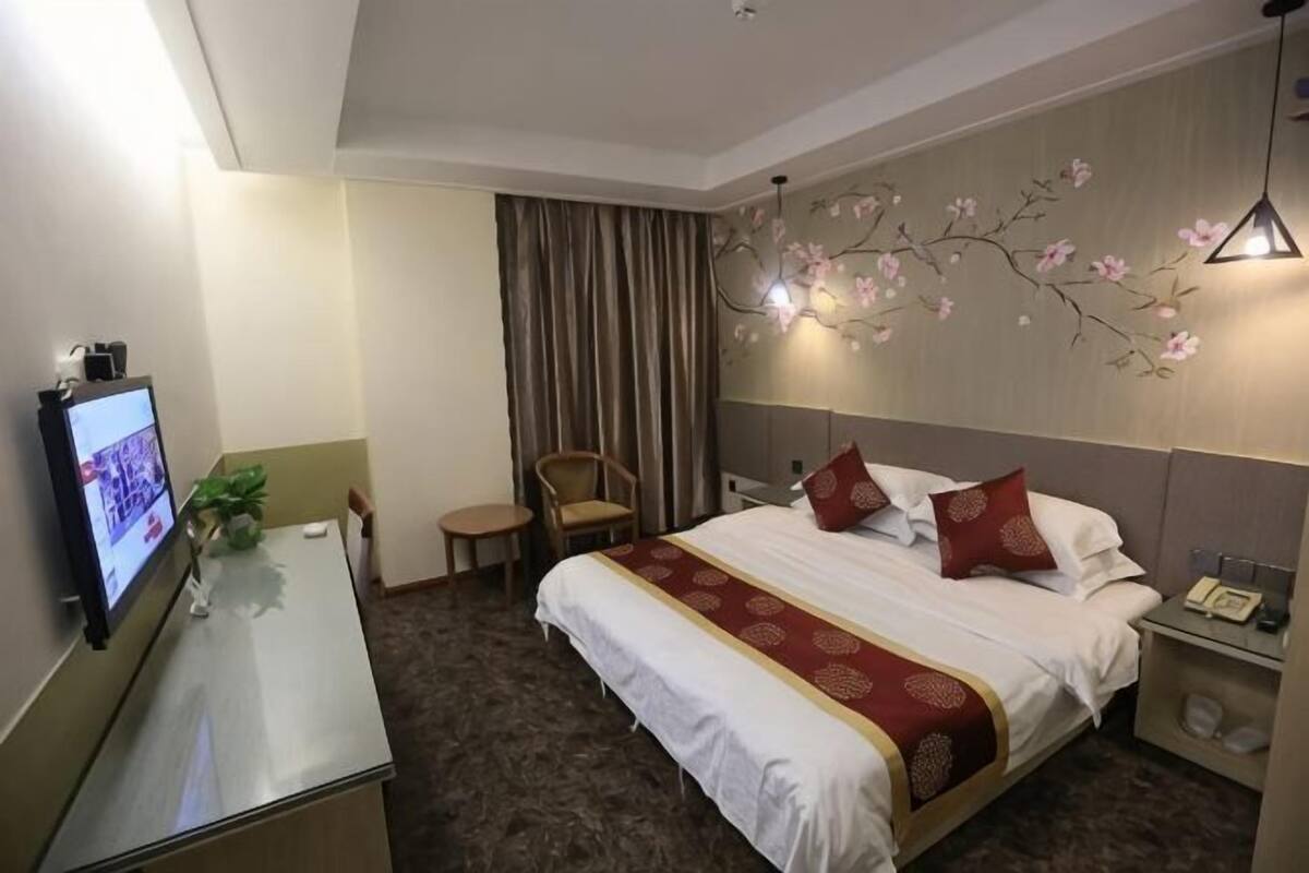 Een hotelkamer met een bed, een bureau met een computer, een stoel en een nachtkastje.