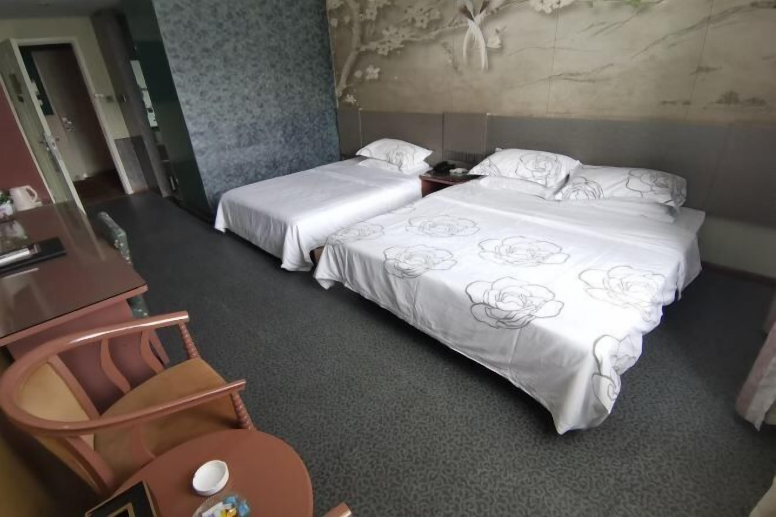 Et hotelværelse med to senge, et skrivebord og en stol.