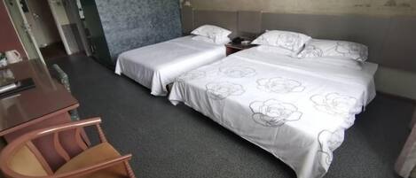 Une chambre d’hôtel avec deux lits, un bureau et une chaise.