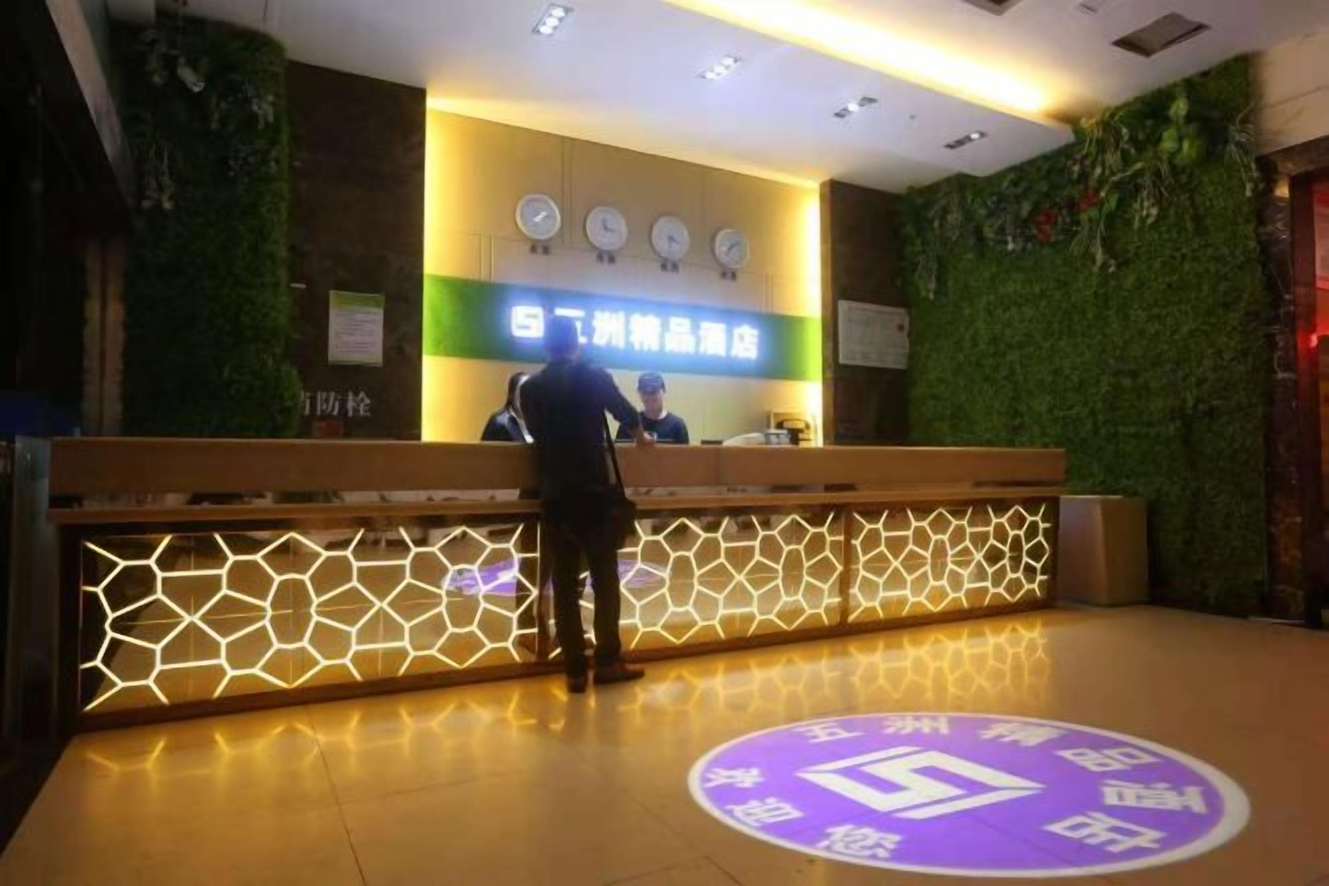 Un mostrador de recepción de diseño moderno, una pared verde y un reloj.