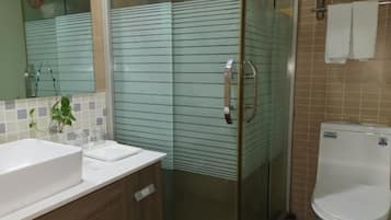 A bathroom with a glass shower enclosure, a white sink, and a toilet.