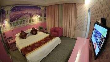 A hotel room with a large bed, a TV, a pink chair, and a mural on the wall.