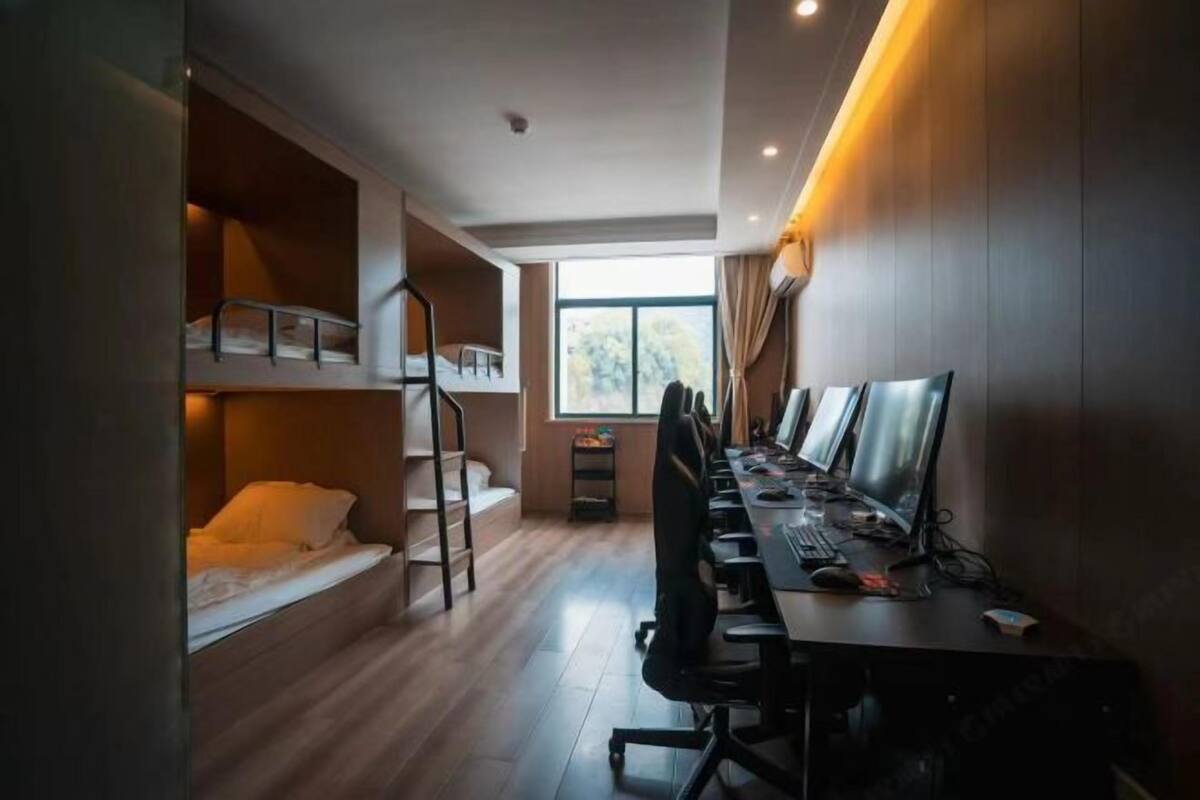 Een kamer met stapelbedden, een bureau met een computer en een raam met uitzicht.