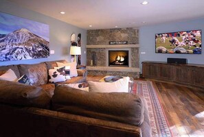 A cozy living room with a fireplace, a mounted TV, and a large painting on the wall.