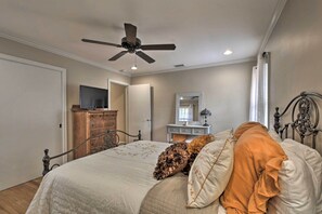 A bedroom with a bed, dresser, mirror, ceiling fan, and a door leading to another room. - Charming Florence Getaway w/ Fireplace & Grill! (Florence)