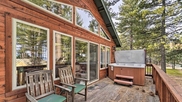 Een houten terras met twee stoelen en een jacuzzi.