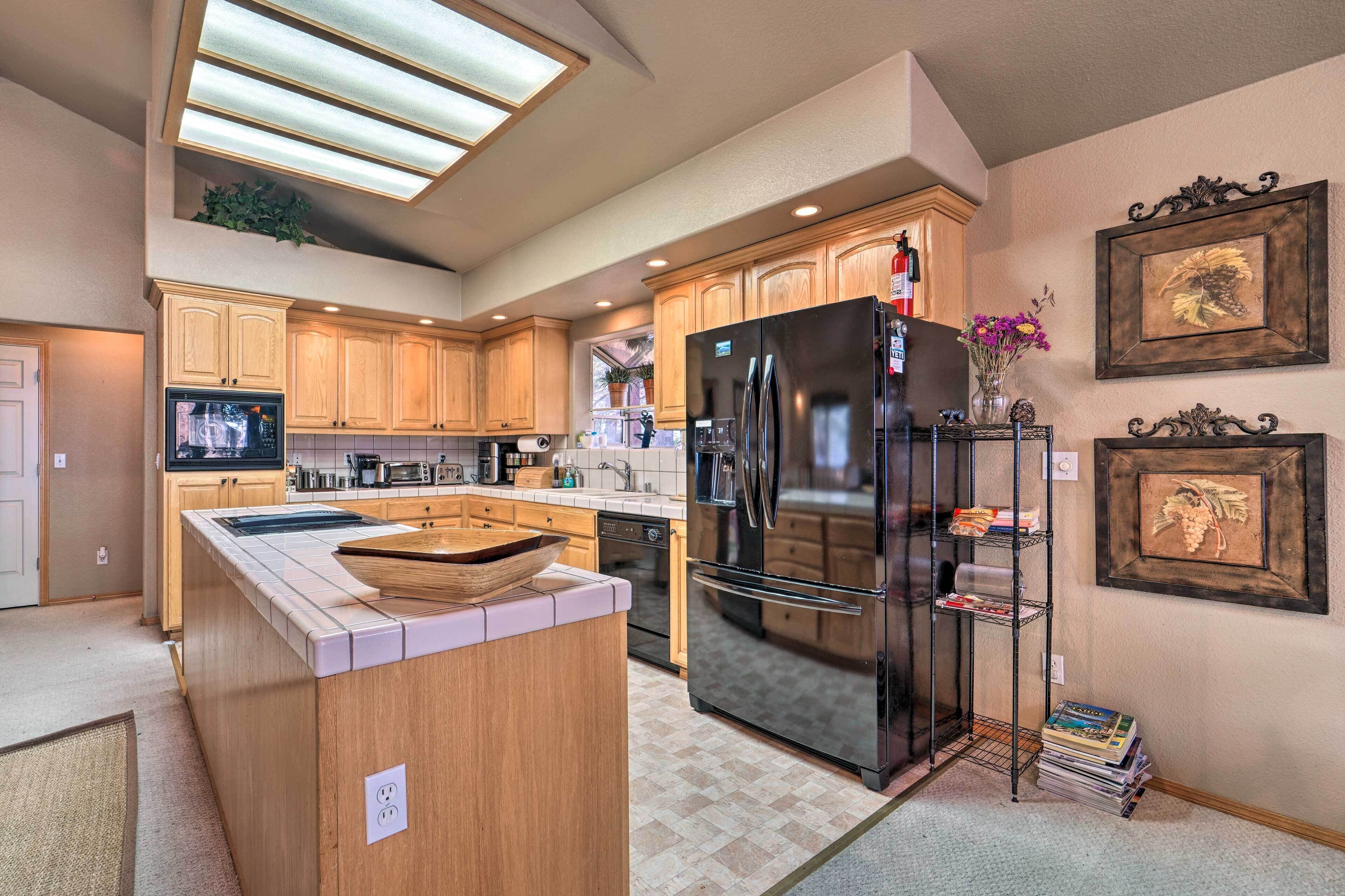 A modern kitchen with wooden cabinets, a black refrigerator, and a built-in oven.