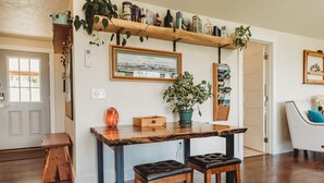 A wooden dining table with two chairs, a potted plant, and a framed picture on the wall. - Charming Hilltop Getaway - Valley and Water Views (Sequim)