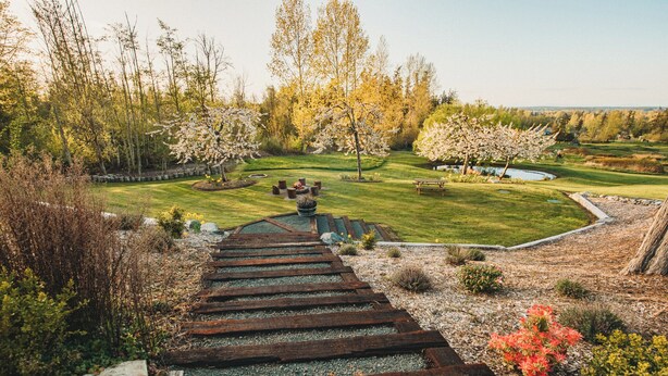 A wooden staircase leading to a garden with a pond, surrounded by trees and shrubs. - Charming Hilltop Getaway - Valley and Water Views (Sequim)