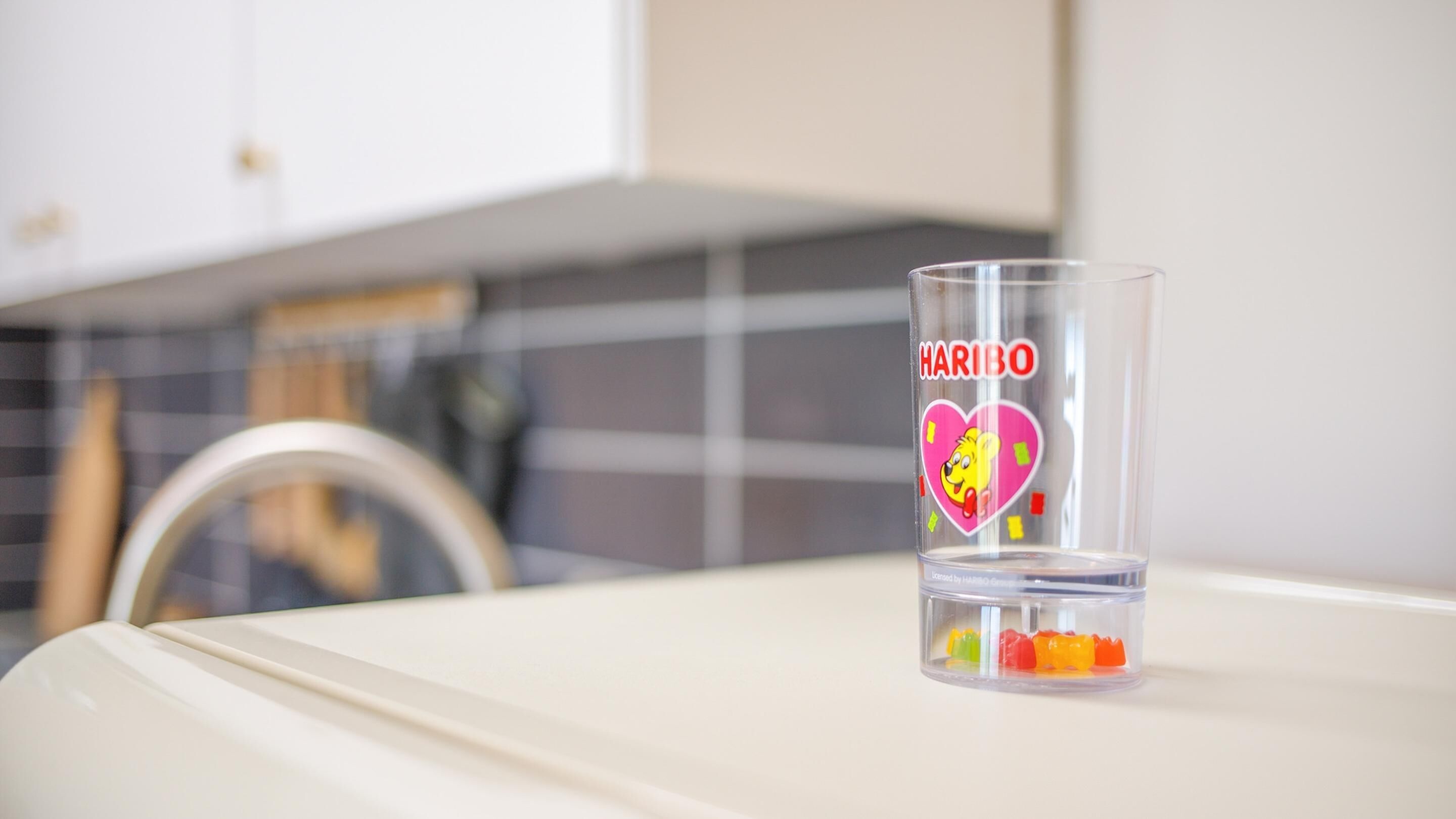 A clear glass with 'HARIBO' and a heart design on a table.