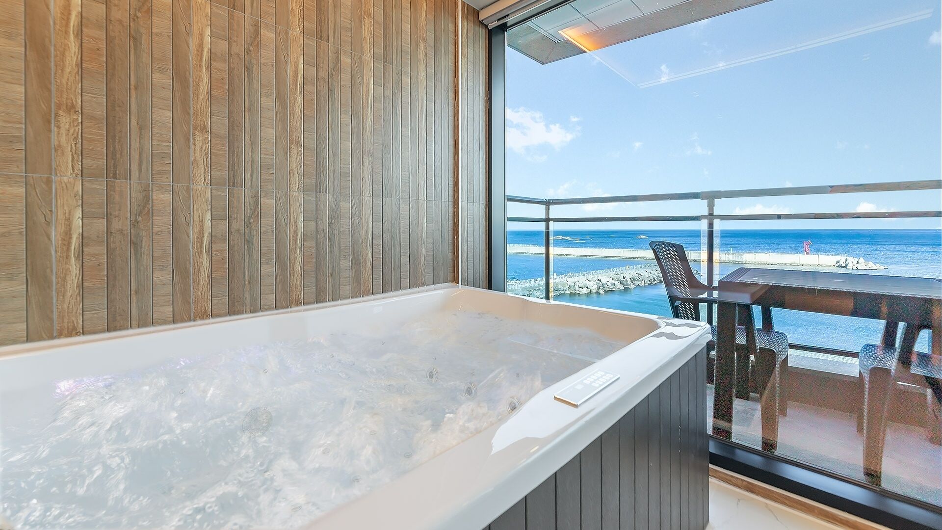 A room with a large bathtub, wooden panel walls, and a view of the ocean.
