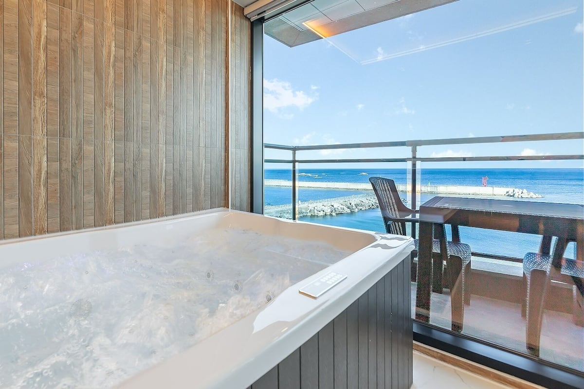Une chambre dotée d’une grande baignoire, de murs lambrissés et offrant une vue sur l’océan.