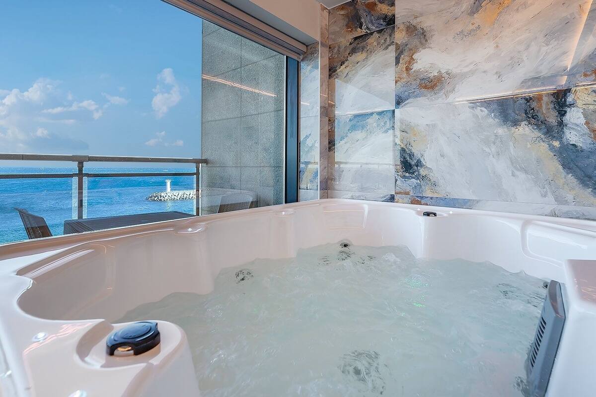 Un jacuzzi con vista al océano y una pared de piedra.