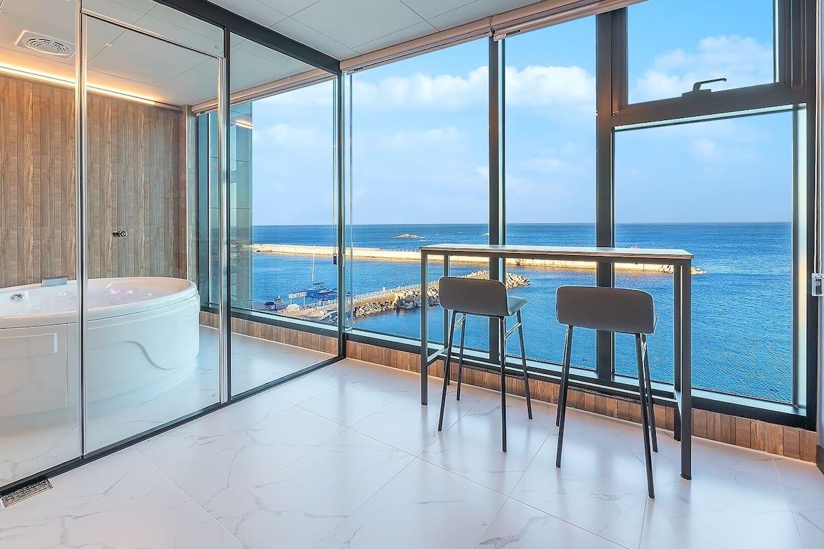 Une salle de bain moderne avec un jacuzzi, une paroi en verre et une vue sur la mer.