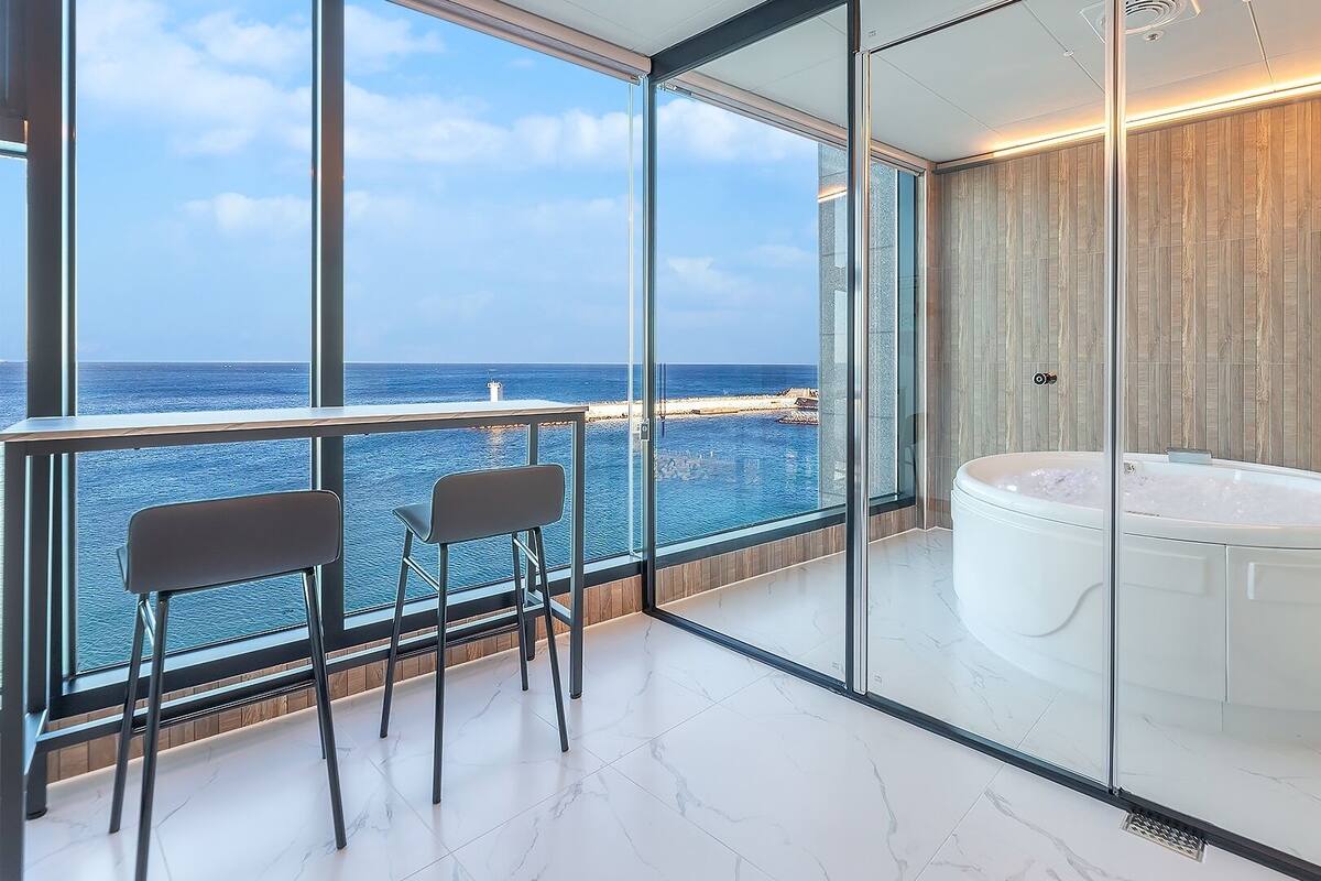 Un balcón con vista al mar, un jacuzzi y una zona de estar con sillas.