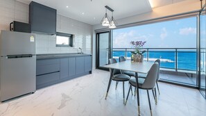 A modern kitchen with a view of the sea, a dining area with a table and chairs, and a large window. - Sokcho The Sharp Pension (Sokcho)