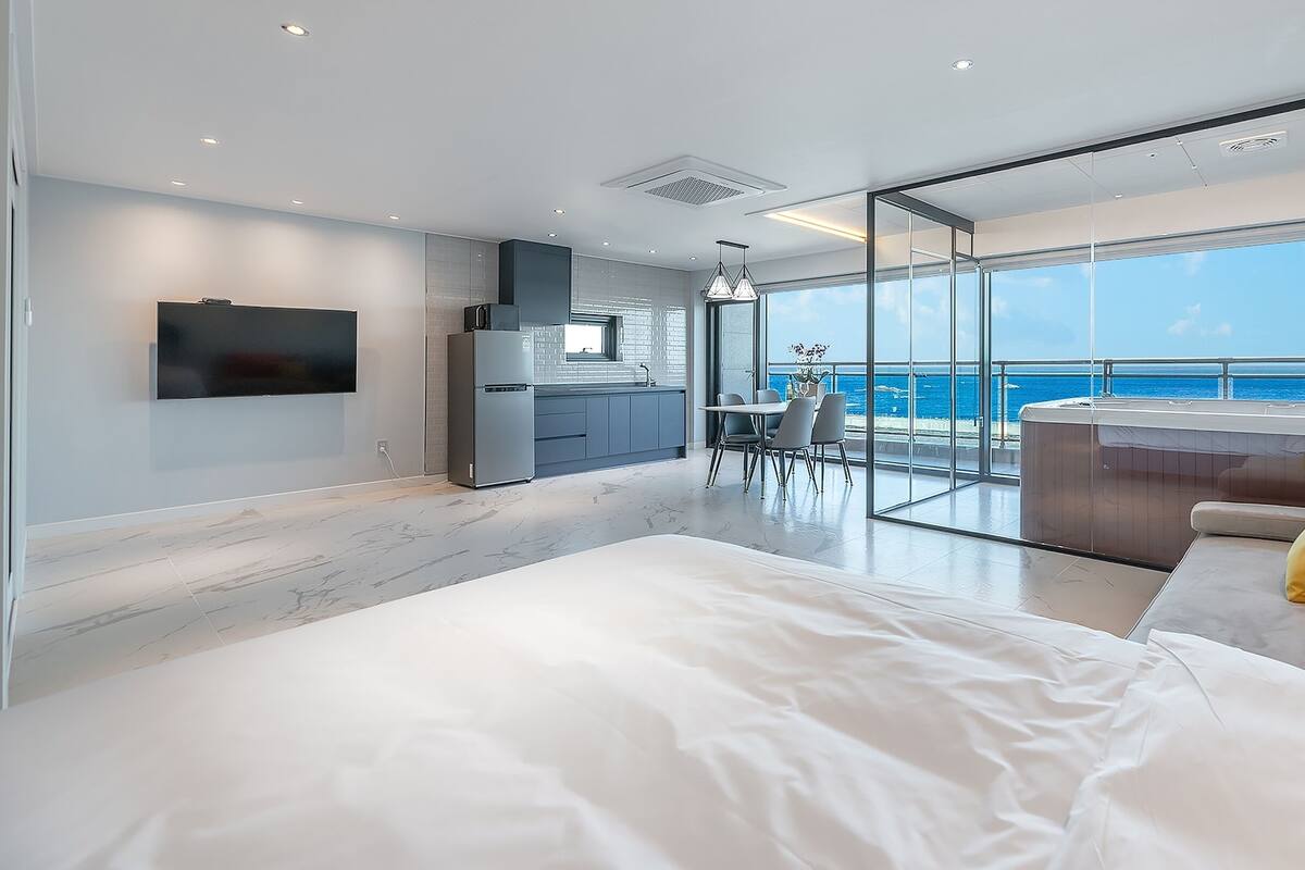 Un dormitorio moderno con una cama grande, un balcón con bañera de hidromasaje y una zona de cocina.
