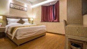 A hotel room with a bed, a nightstand, a lamp, a window with curtains, and a wooden floor. - Great Wall Hotel (Xiamen)