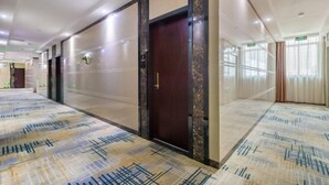 A hotel corridor with patterned carpet, a dark wooden door, and a mirrored wall. - Fuxiang Hotel (Foshan Shunde Lunjiao Branch) (Foshan)
