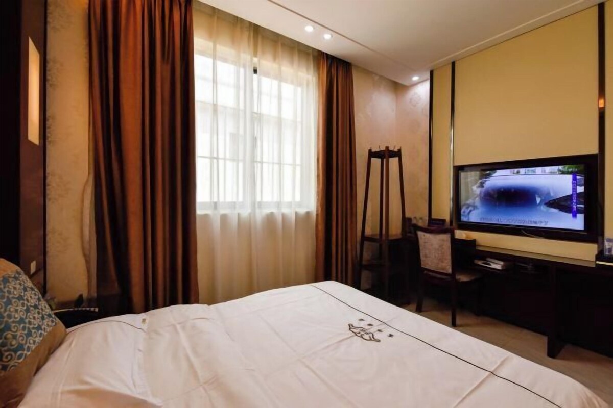 Habitación de hotel con cama, televisión, escritorio y una silla.