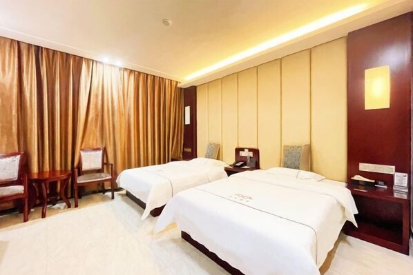 Habitación de hotel con dos camas, un escritorio, una silla y un ventanal con cortinas.