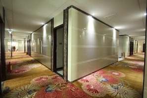 Un pasillo de hotel con paredes espejadas y piso alfombrado.