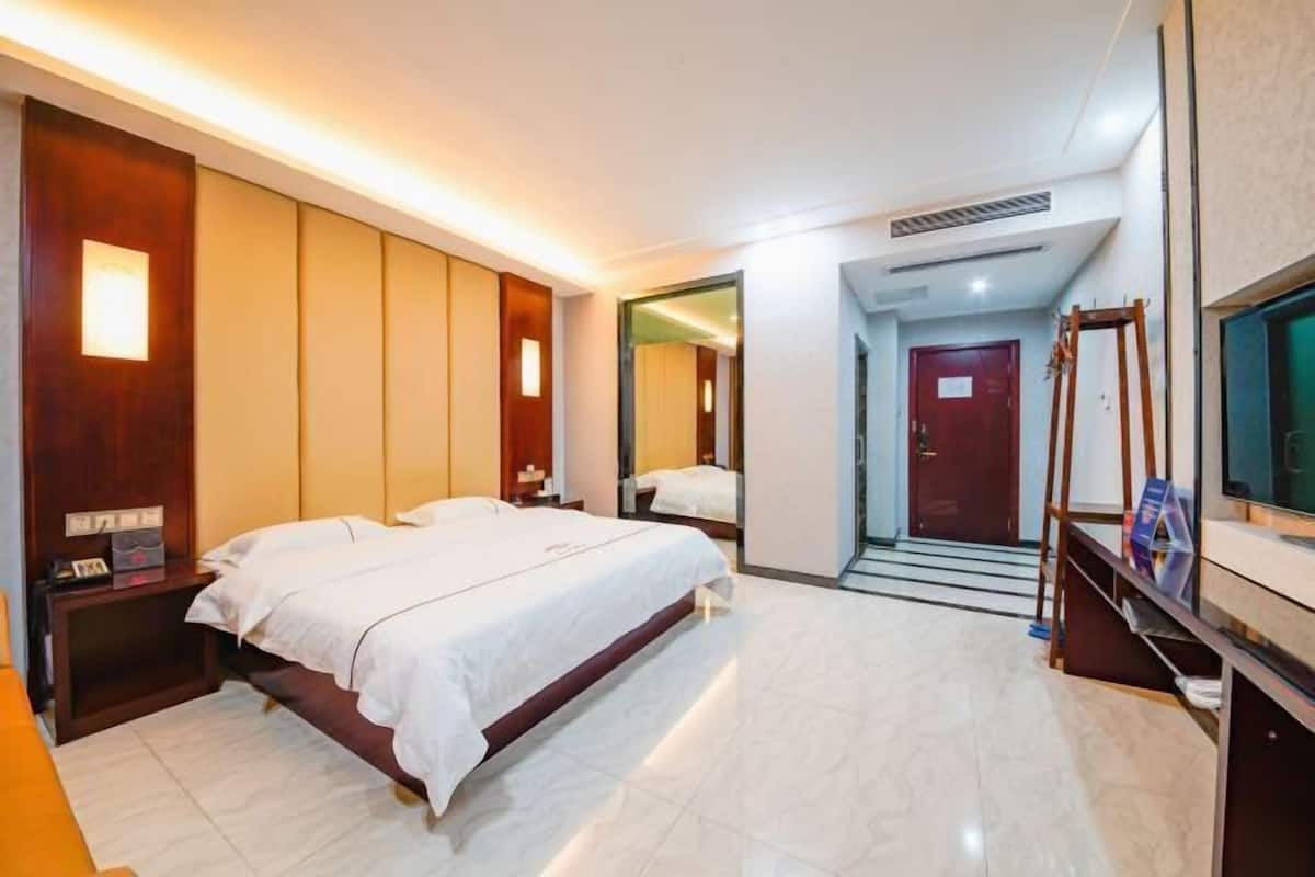 A hotel room with two beds, a TV, a mirror, and a staircase leading to another room.