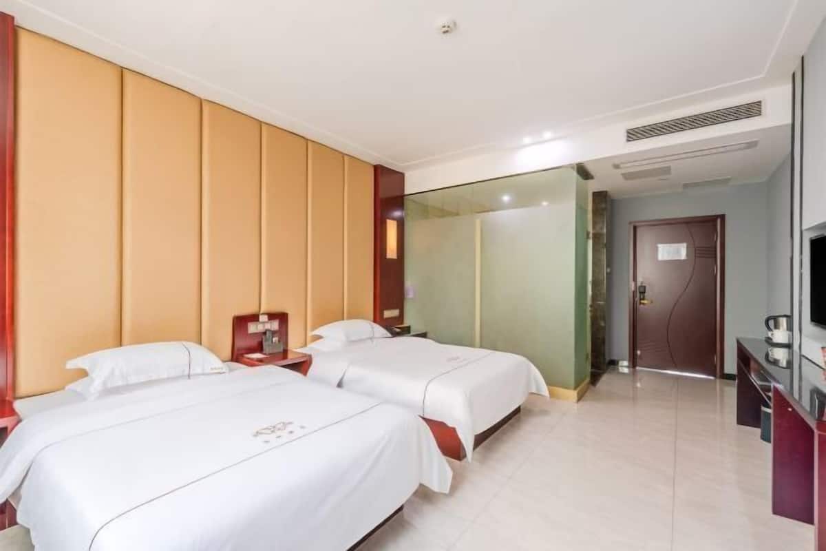 A hotel room with two beds, a TV, and a minibar.