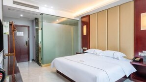 A hotel room with a large bed, a bedside table, a mirror, a wardrobe, and a door leading to another room. - Fuxiang Hotel (Foshan Shunde Lunjiao Branch) (Foshan)