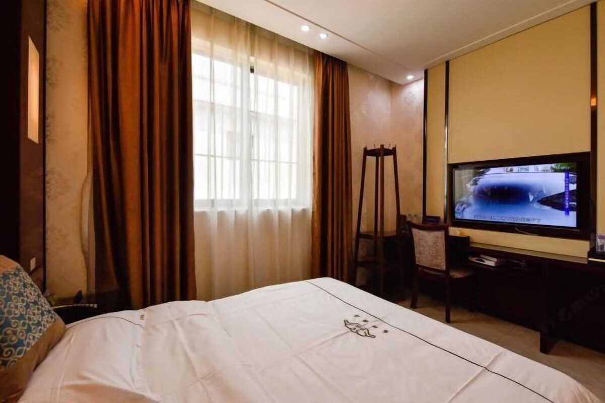 Una habitación de hotel con cama, televisor, escritorio y una silla.