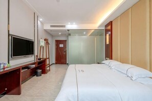 A hotel room with a bed, a TV, a desk, and a mirror.